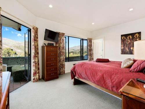 a bedroom with a red bed and a large window at Kawarau Bay View - Cromwell Holiday Home in Cromwell