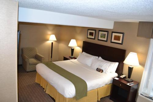 a hotel room with a large bed and a chair at Holiday Inn Express Boston Brockton by IHG in Brockton