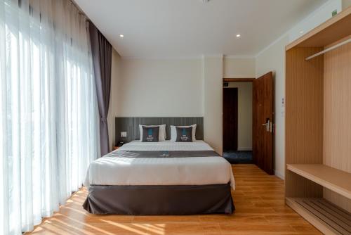 a bedroom with a bed and a large window at The Empire Hotel in Phu Quoc