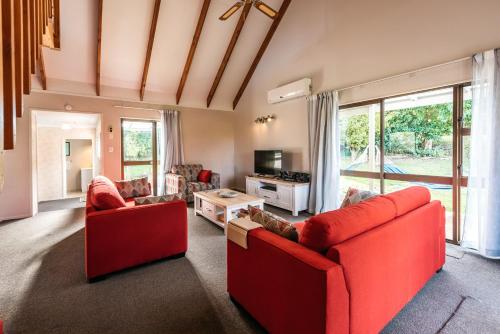 a living room with two red couches and a table at Oneroa Oasis - Oneroa Holiday Home in Oneroa