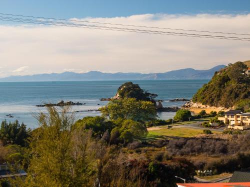 a view of the ocean with mountains in the background at Beach House on the Ridge - Kaiteriteri House in Kaiteriteri