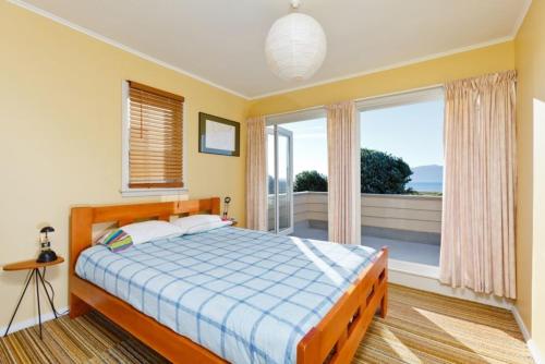sypialnia z łóżkiem i dużym oknem w obiekcie Beach House - Paraparaumu Beach Holiday Home w mieście Paraparaumu Beach