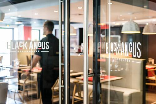 a man standing in front of a restaurant window at Holiday Inn Toulouse Airport by IHG in Blagnac