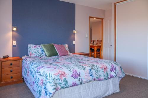 a bedroom with a large bed with a floral bedspread at Hanmer's Rose - Hanmer Springs Holiday Home in Hanmer Springs