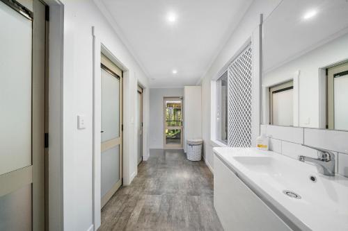 La salle de bains blanche est pourvue d'un lavabo et d'un miroir. dans l'établissement The Bunkhouse - The Lodge Te Horo, à Te Horo