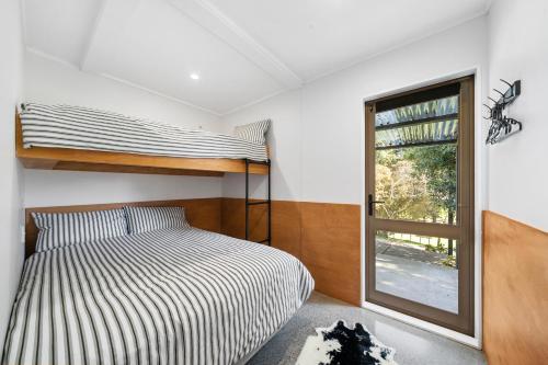 een slaapkamer met een stapelbed en een raam bij The Bunkhouse - The Lodge Te Horo in Te Horo