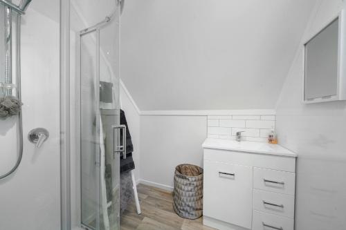 a white bathroom with a sink and a shower at The Apartment - The Lodge Te Horo in Te Horo