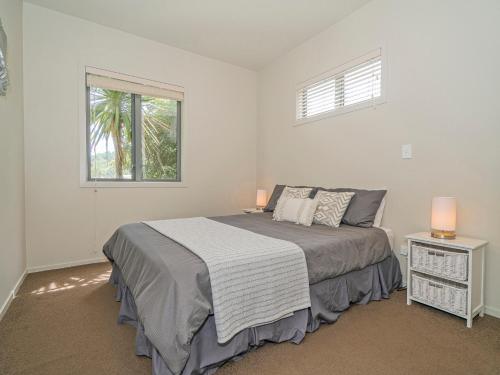 1 dormitorio con 1 cama con 2 lámparas y una ventana en Lakeside Villa Retreat - Matarangi Downstairs Unit, en Matarangi