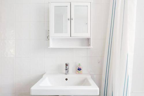 ein Badezimmer mit einem weißen Waschbecken und einem weißen Schrank in der Unterkunft Eagle Drive in Hendon
