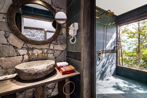 a stone bathroom with a sink and a mirror at Sapa Catcat Hills Resort & Spa in Sa Pa