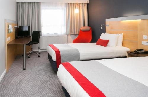 a hotel room with two beds and a desk at Holiday Inn Express Antrim by IHG in Antrim