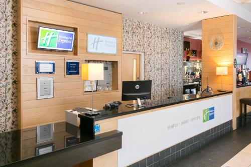 a restaurant with a reception counter with a computer on the wall at Holiday Inn Express Antrim by IHG in Antrim