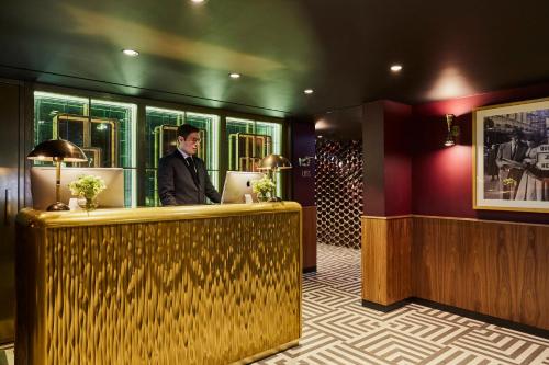 a man standing behind a bar in a hotel lobby at Hotel Indigo London - 1 Leicester Square by IHG in London