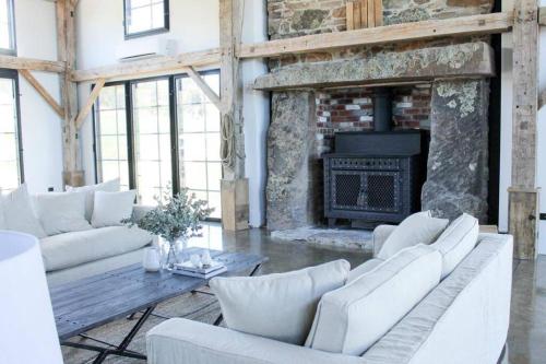 a living room with white furniture and a fireplace at Coombs Hill Barn in Merrijig