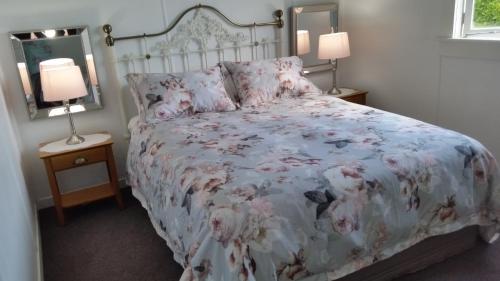 um quarto com uma cama com colcha floral e 2 candeeiros em The White House Taihape em Taihape