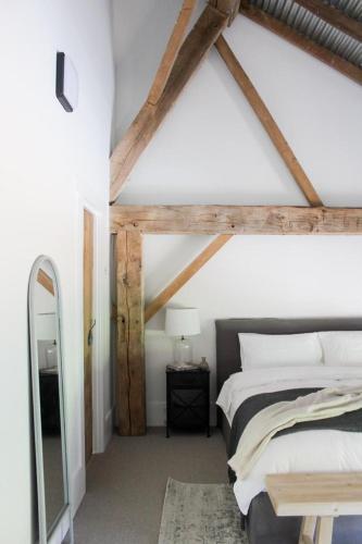 a bedroom with a large bed and a mirror at Coombs Hill Barn in Merrijig