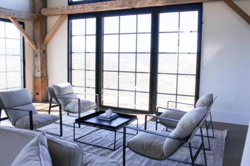 a living room with chairs and a table and windows at Coombs Hill Barn in Merrijig