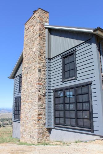 a building with two windows and a brick chimney at Coombs Hill Barn in Merrijig