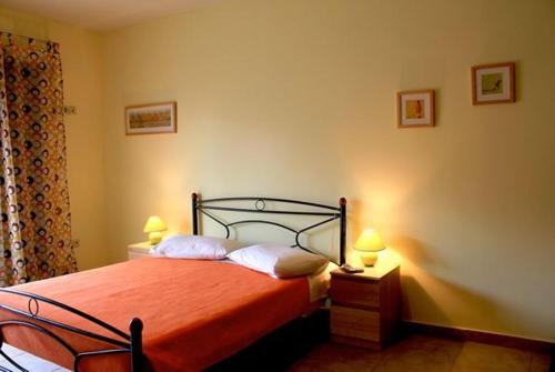 a bedroom with a bed with orange sheets and two lamps at The Seasons of Nickolas in Ayia Evfimia