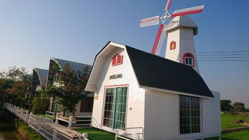 a white church with a windmill on top of it at ข้าวทุ่งเบ็ญจาโฮมสเตย์ in Ban Hat Phang