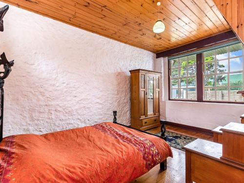 a bedroom with a bed and a desk and a window at The Stables in Port Fairy