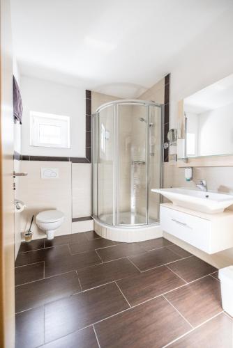 a bathroom with a shower and a toilet and a sink at Hotel Germania in Stadtallendorf