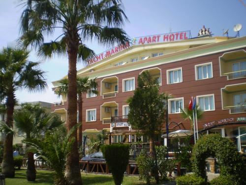 a large building with palm trees in front of it at Blue Yacht Marina Apart Hotel in Marmaris