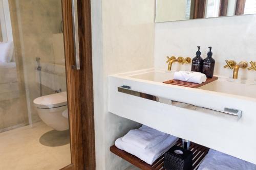 ein Badezimmer mit einem Waschbecken, einem WC und einem Spiegel in der Unterkunft Harding Boutique Hotel in Ahangama
