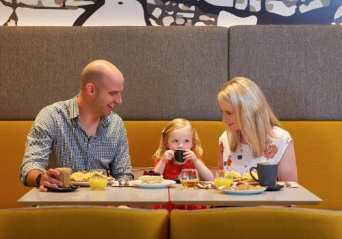 a man and two children sitting at a table eating food at Holiday Inn Express Melbourne Southbank by IHG in Melbourne