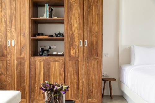 a bedroom with a wooden cabinet with a vase of flowers at Harding Boutique Hotel in Ahangama