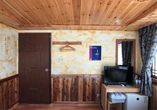 a room with a door and a television on a table at Gudeok Guesthouse in Seogwipo