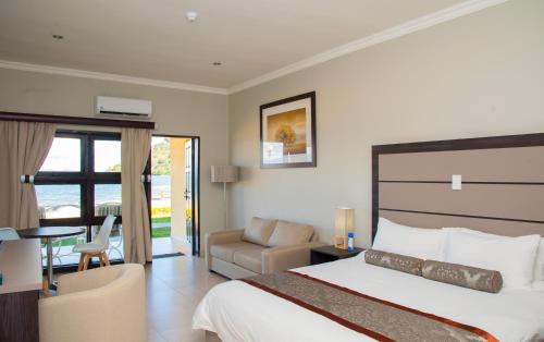 a bedroom with a bed and a couch and a chair at Sunbird Nkopola in Chipoka