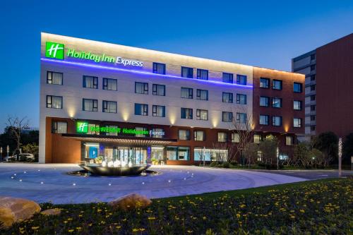 a hotel building with a fountain in front of it at Holiday Inn Express Shanghai Kangqiao by IHG in Shanghai
