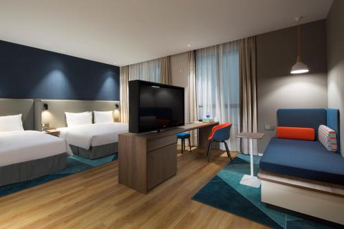 a hotel room with two beds and a flat screen tv at Holiday Inn Express Shanghai Kangqiao by IHG in Shanghai