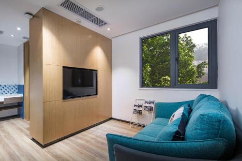 a living room with a blue couch and a television at Holiday Inn Express Shanghai Kangqiao by IHG in Shanghai