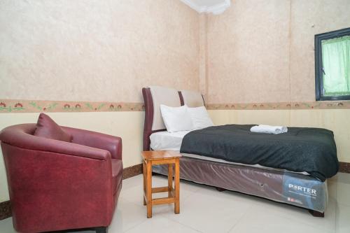 a bedroom with a bed and a chair at Hotel Transit Nusa Indah near Soekarno Hatta Airport Mitra RedDoorz in Tangerang