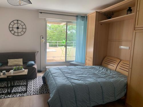 a bedroom with a bed and a couch and a window at Grand studio Clémenceau Vue mer 3 étoiles in Pléneuf-Val-André