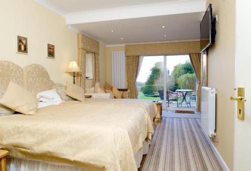 a hotel room with two beds and a television at Tyn Rhos Country House in Caernarfon