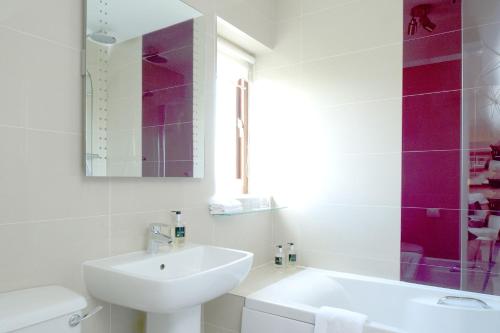 a white bathroom with a sink and a mirror at Tyn Rhos Country House in Caernarfon