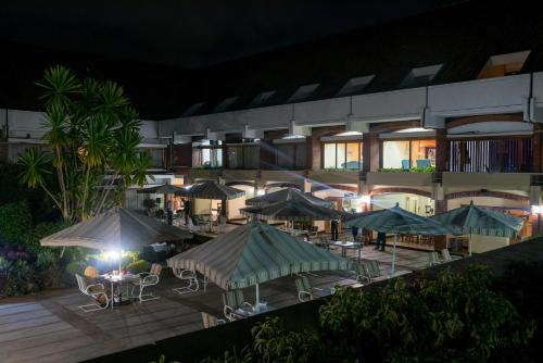an outdoor restaurant with tables and umbrellas at night at Sunbird Capital in Lilongwe