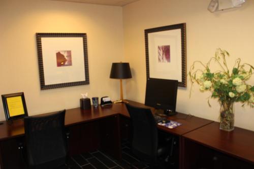 an office with a desk with a computer and a vase of flowers at Holiday Inn Express Hotel & Suites - Atlanta/Emory University Area by IHG in Decatur