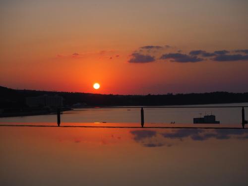 a sunset over a body of water with the sun setting at Hiyori Ocean Resort Okinawa in Onna