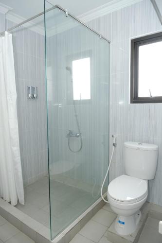 a bathroom with a toilet and a glass shower at Joyful Hotel in Tanjungpandan