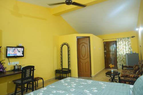 a bedroom with a bed and a tv and a couch at John's Highland Comfort (Guest House) in Majorda
