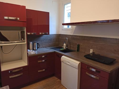 une cuisine avec des armoires rouges et un réfrigérateur blanc dans l'établissement T2 Toulouse Saint cyprien 40m2 indépendant, quartier sympa, 1er étage sur 2, Terrasse, à Toulouse