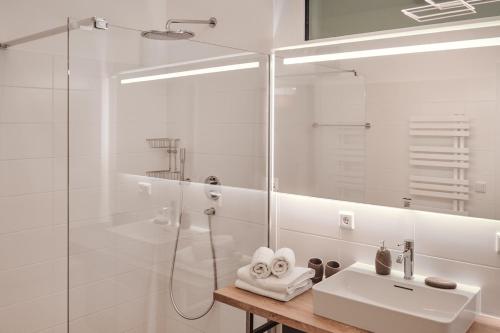 a white bathroom with a shower and a sink at die Tauplitz Lodges - Wasserfall Lodge C2 by AA Holiday Homes in Tauplitz