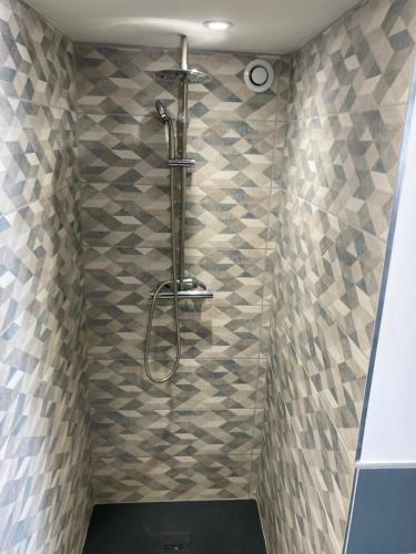 y baño con ducha y pared de azulejos. en studio meublé du bourg en Puymiclan