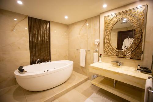 拉合爾的住宿－Nine Tree Luxury Hotel & Suites Lahore，带浴缸、水槽和镜子的浴室