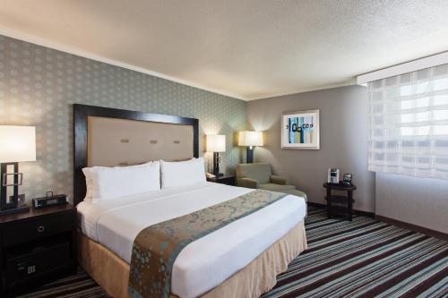 a hotel room with a large bed and a chair at Holiday Inn Long Beach - Airport by IHG in Long Beach