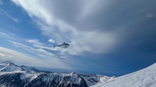 a helicopter is flying over a snow covered mountain at Hlíðarvegur 20 - Gagginn in Siglufjörður